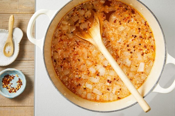 Add garlic, vegetable broth and water; bring to a boil. Add salt, paprika and crushed pepper flakes;