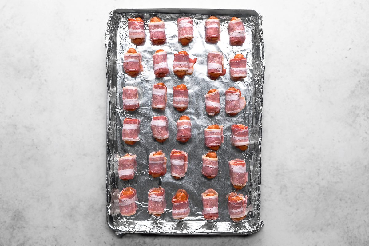wrapped sausages placed in a foil-lined 15x10x1-inch baking pan