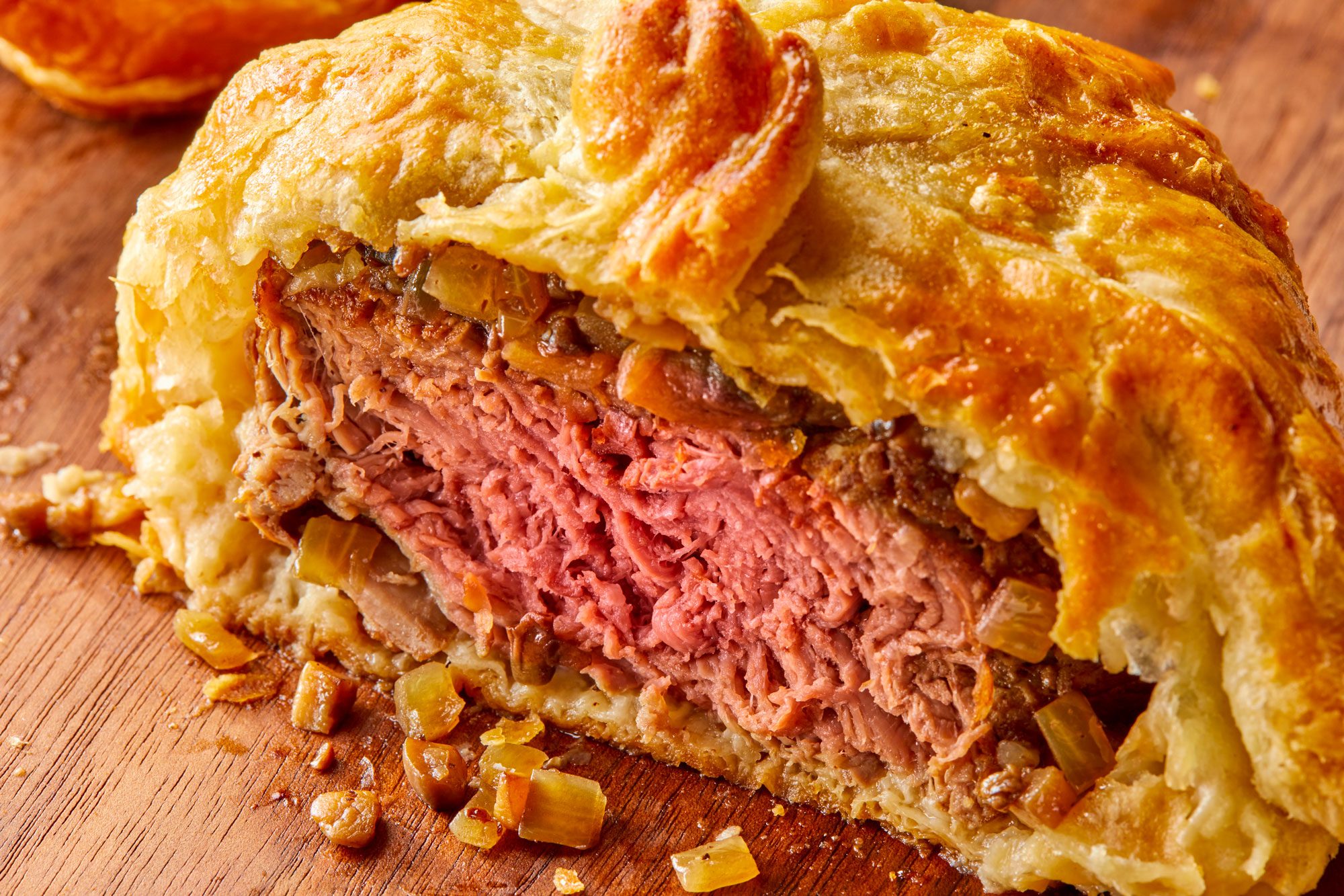3/4th closeup shot of Beef Wellington resting on a wooden cutting board