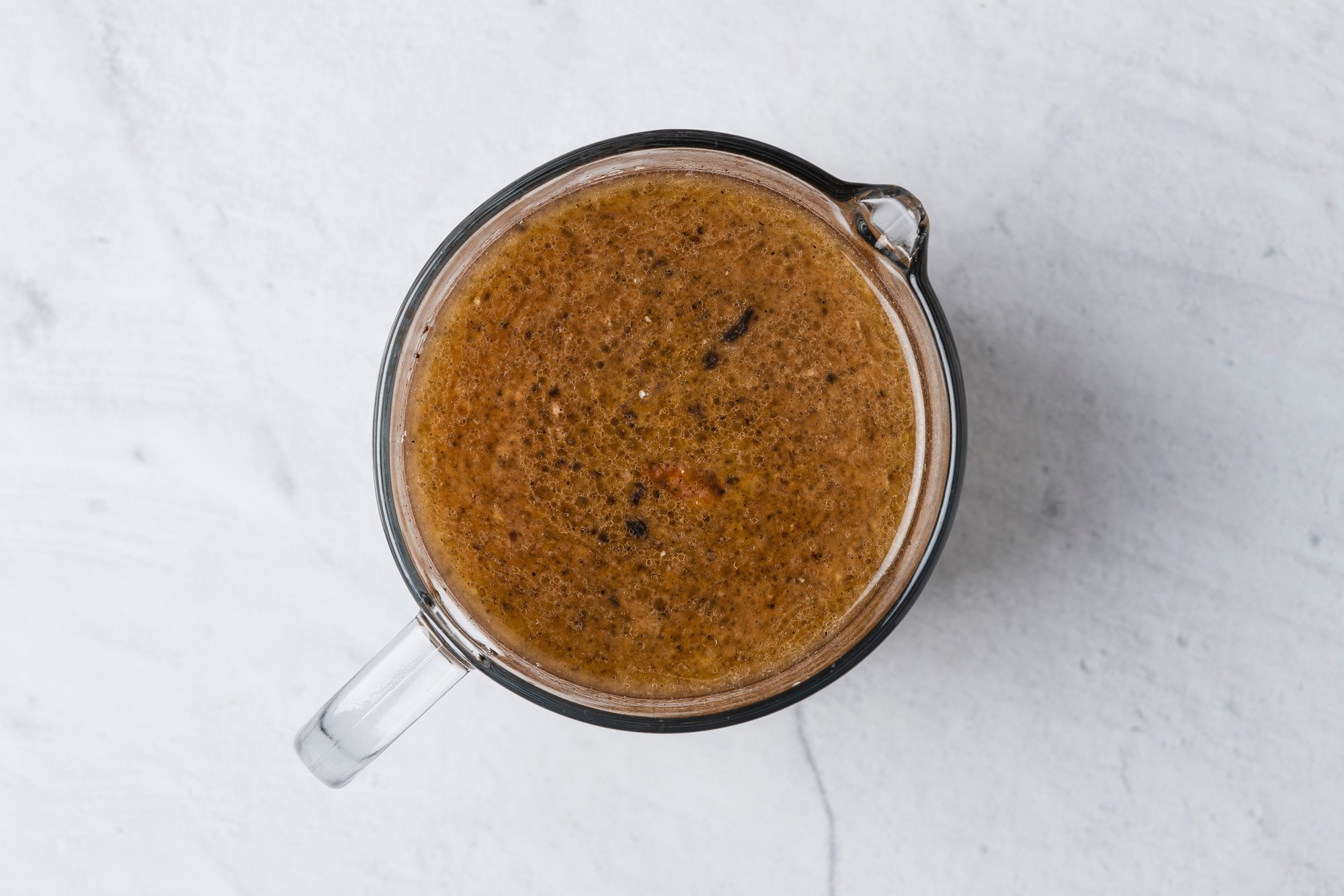 Overhead shot of Pour drippings and loosened brown bits into a measuring cup; Skim fat; reserving 1/3 cup; add enough broth to remaining drippings to measure 4 cups; marble surface;