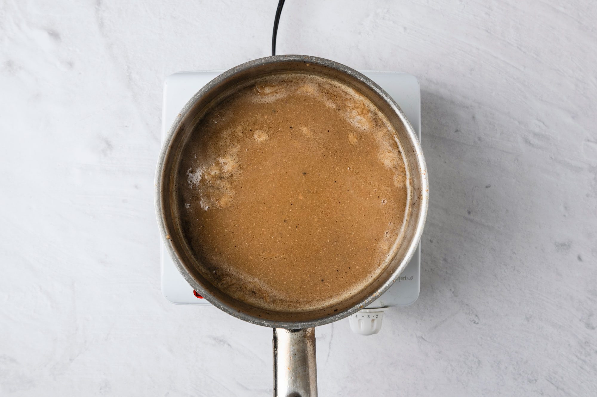 Overhead shot; For gravy chop refrigerated giblets; In a large saucepan; saute giblets in reserved fat until browned; Stir in flour until blended; gradually stir in broth mixture; Bring to a boil; cook and stir until thickened about 2 minutes; marble surface;