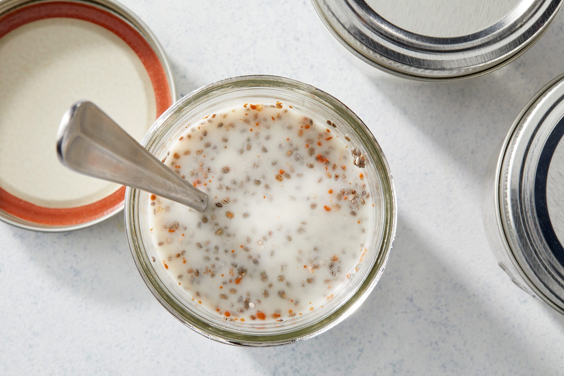 A top view of an open jar filled with a chia seed pudding mixture, with visible seeds in a creamy liquid.