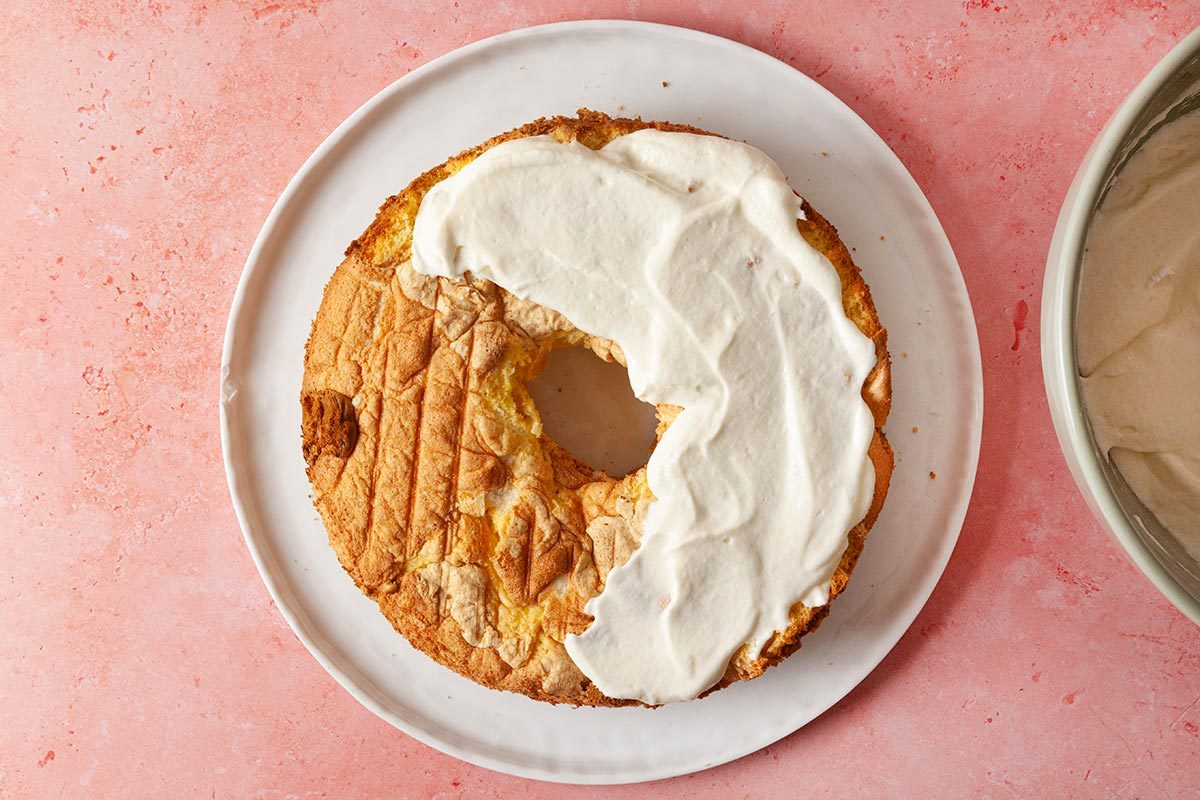 round cake placed on a white plate, with its surface partially covered in a thick layer of cream,