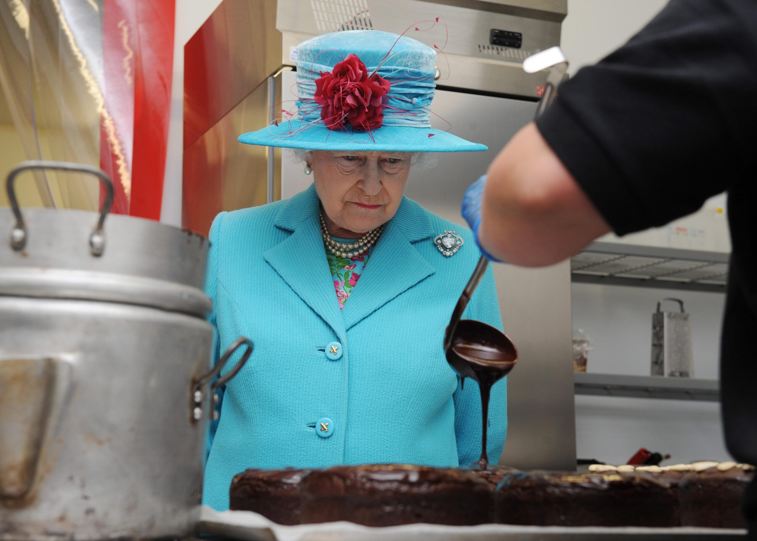 Queen Elizabeth watches chocolate being poured over a cake