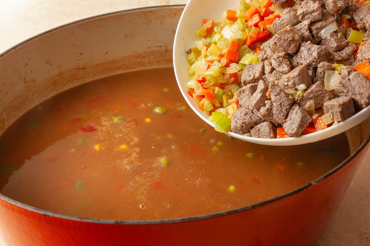 cooked onion, carrot and celery mixture and browned steak bein poured in the soup