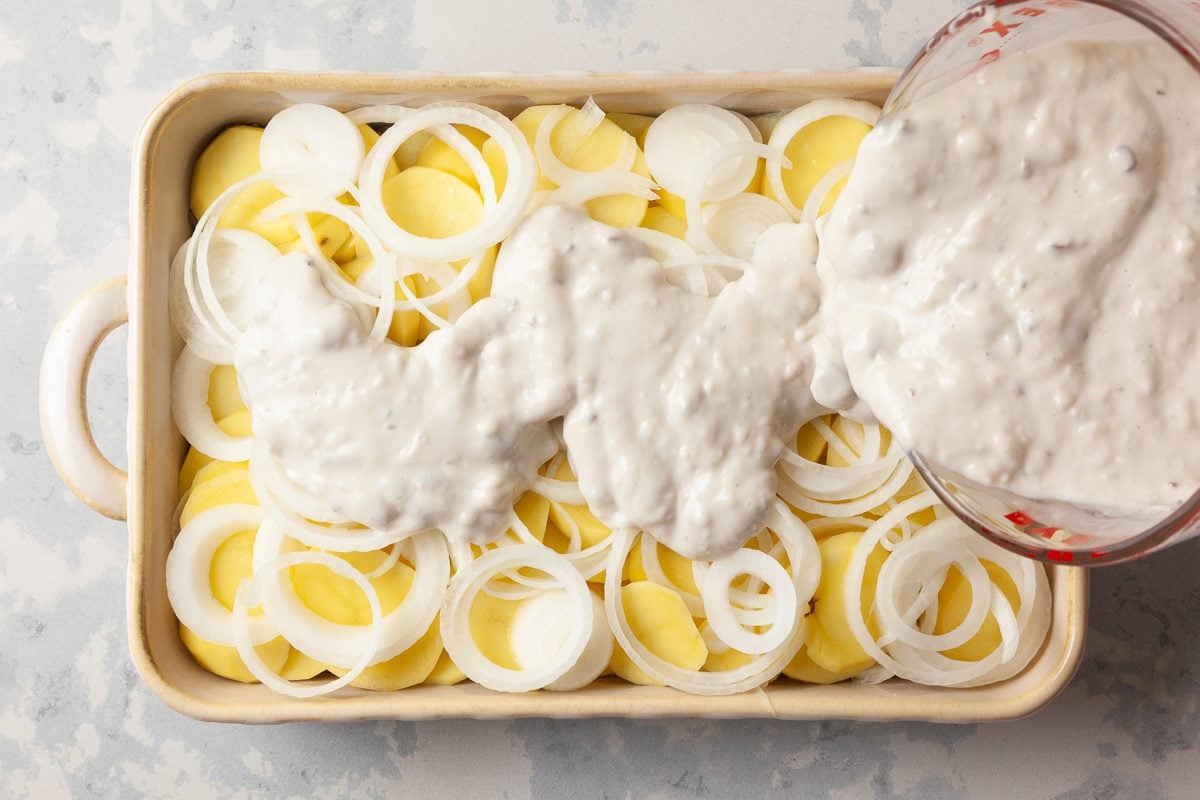 soup and milk mixture being poured over vegetable and beef layers