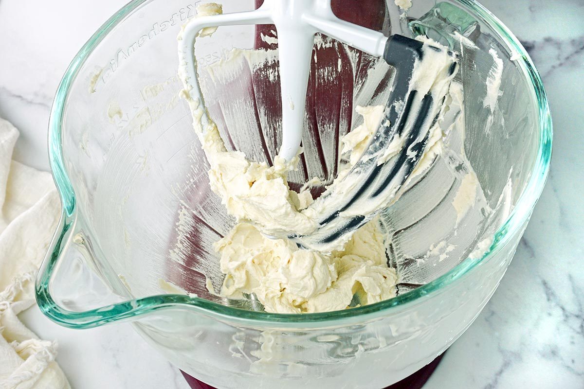 Stand mixer whipping butter in a clear bowl
