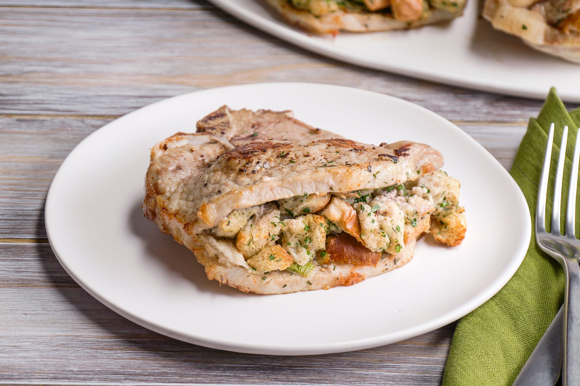 Front shot of Air Fryer Stuffed Pork Chops in a white plate on a wooden table top