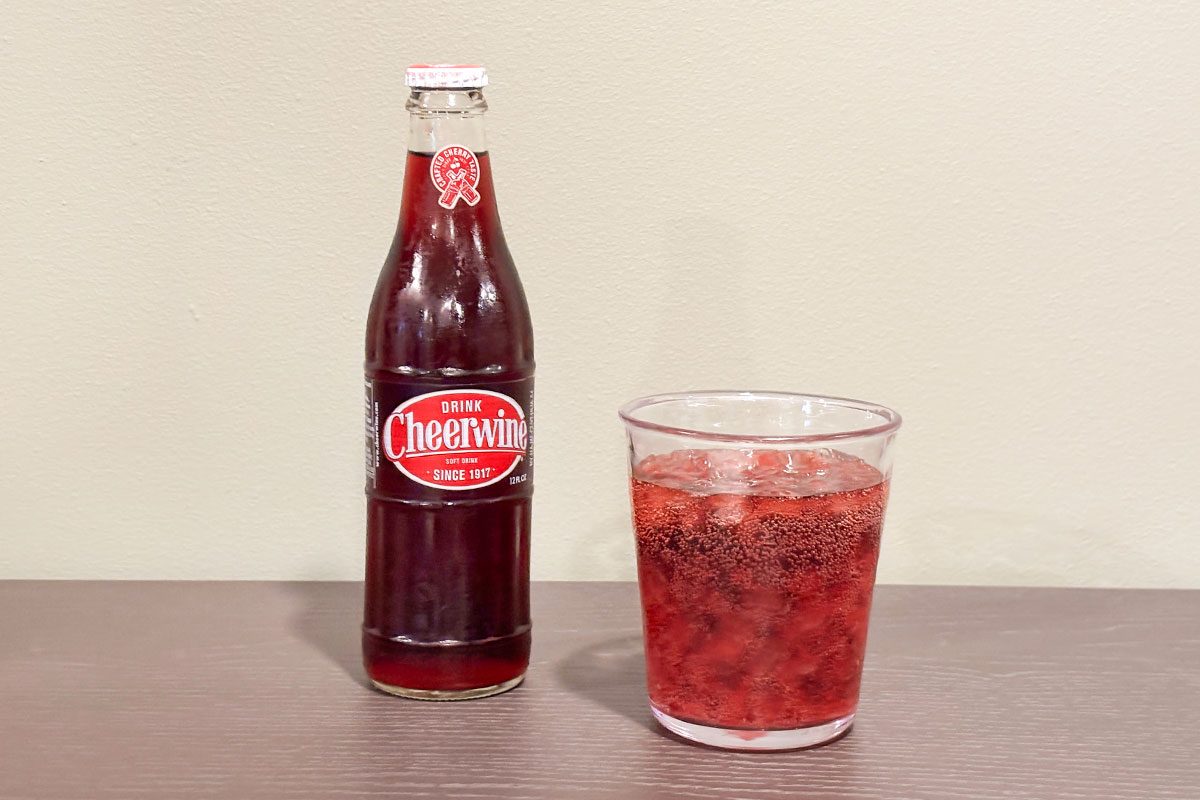 A glass filled with Cheerwine drink placed with cheerwine bottle
