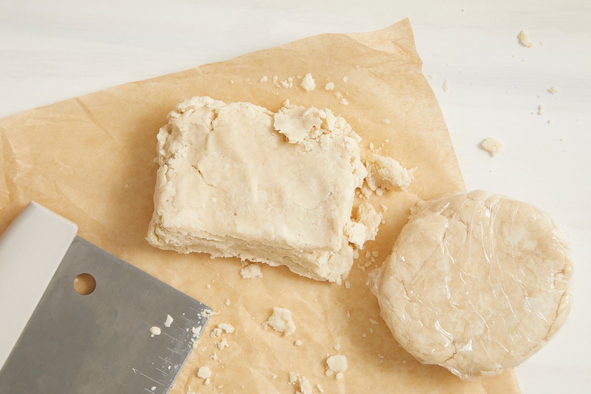 Overhead shot of divide dough in half; Shape each into a disk; wrap and refrigerate 1 hour or overnight; paper sheet; cream surface