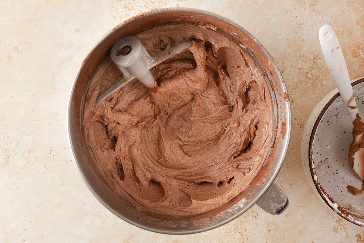 ingredients for chocolate frosting being beated in a mixer