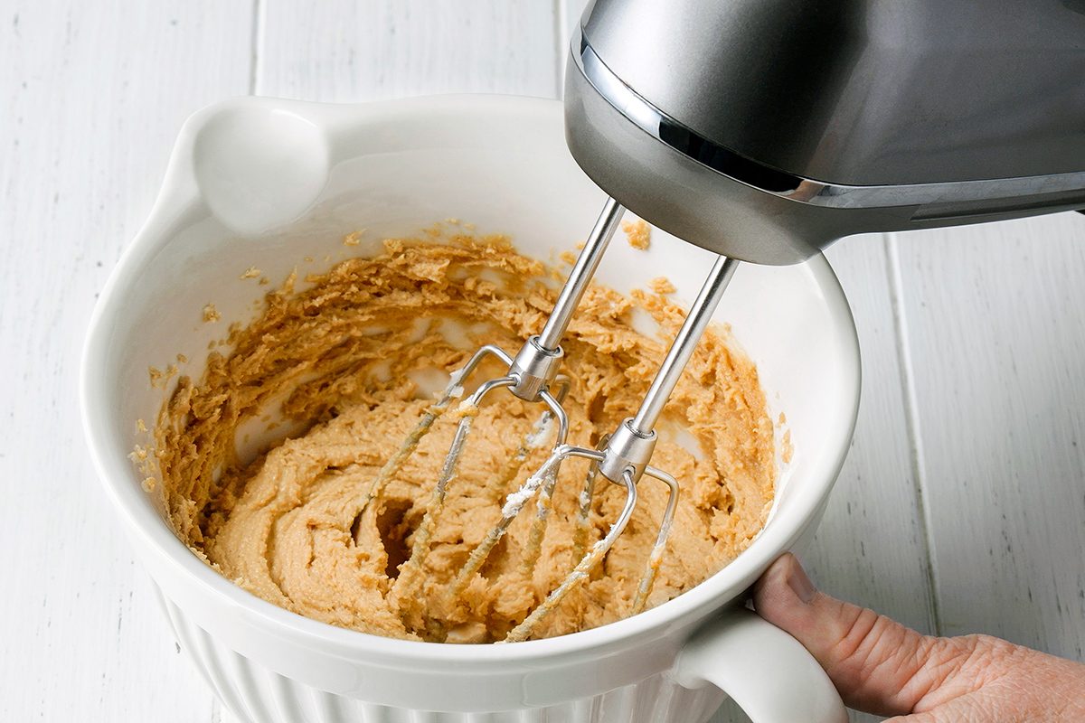 A small glass bowl filled with a white, semi-liquid substance sits on a white wooden surface.