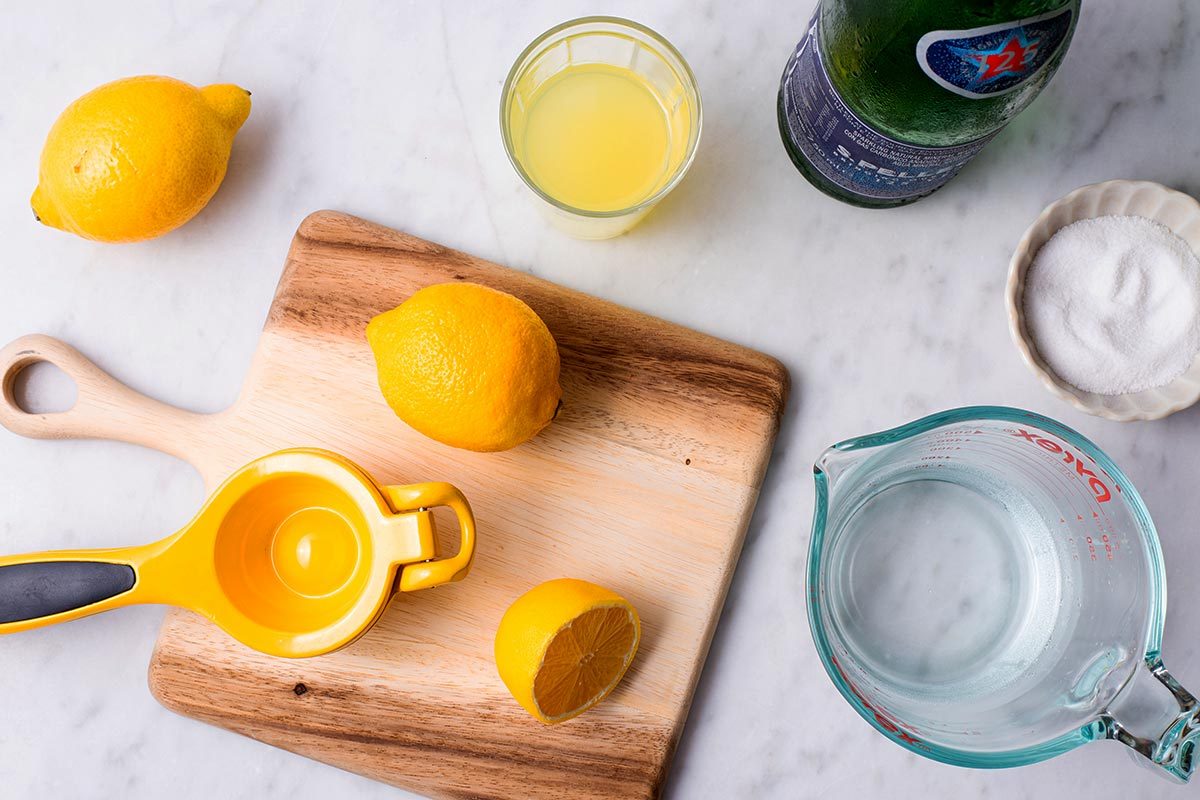 Cut lemons, limoncello, salt, and measuring cups on a cutting board