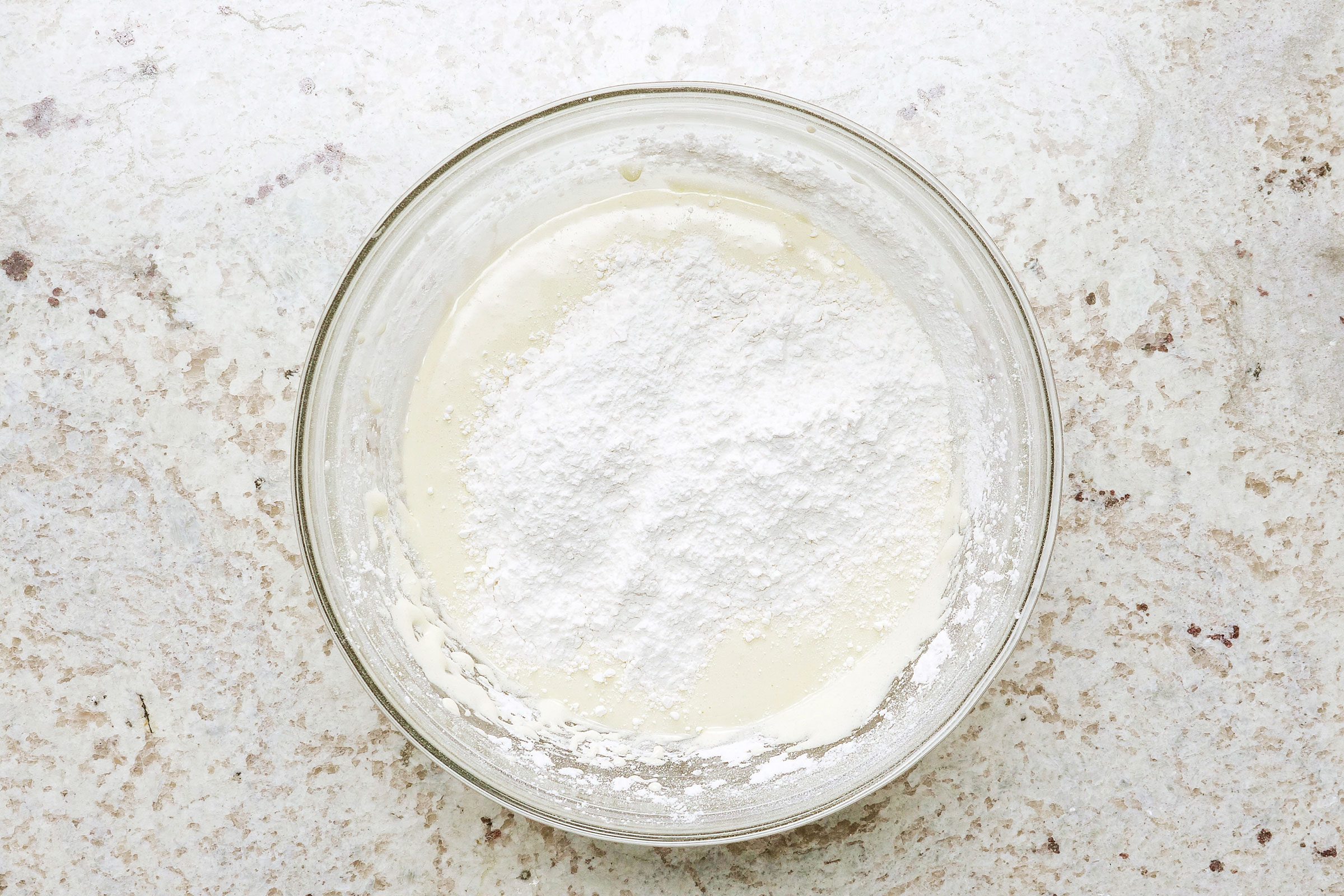 Flour mixture mixed with egg mixture in a large glass bowl.