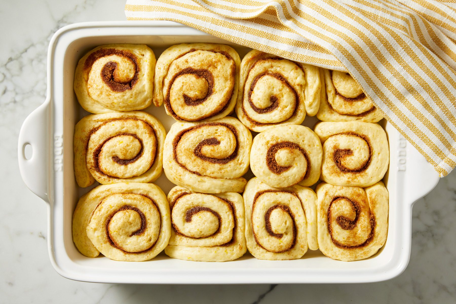 Overhead shot of cover with a kitchen towel; Let rise in a warm place until doubled about 1 hour; Meanwhile, preheat oven to 350 degree; Bake until golden brown 20-25 minutes; Cool on wire racks; napkin; marble surface;