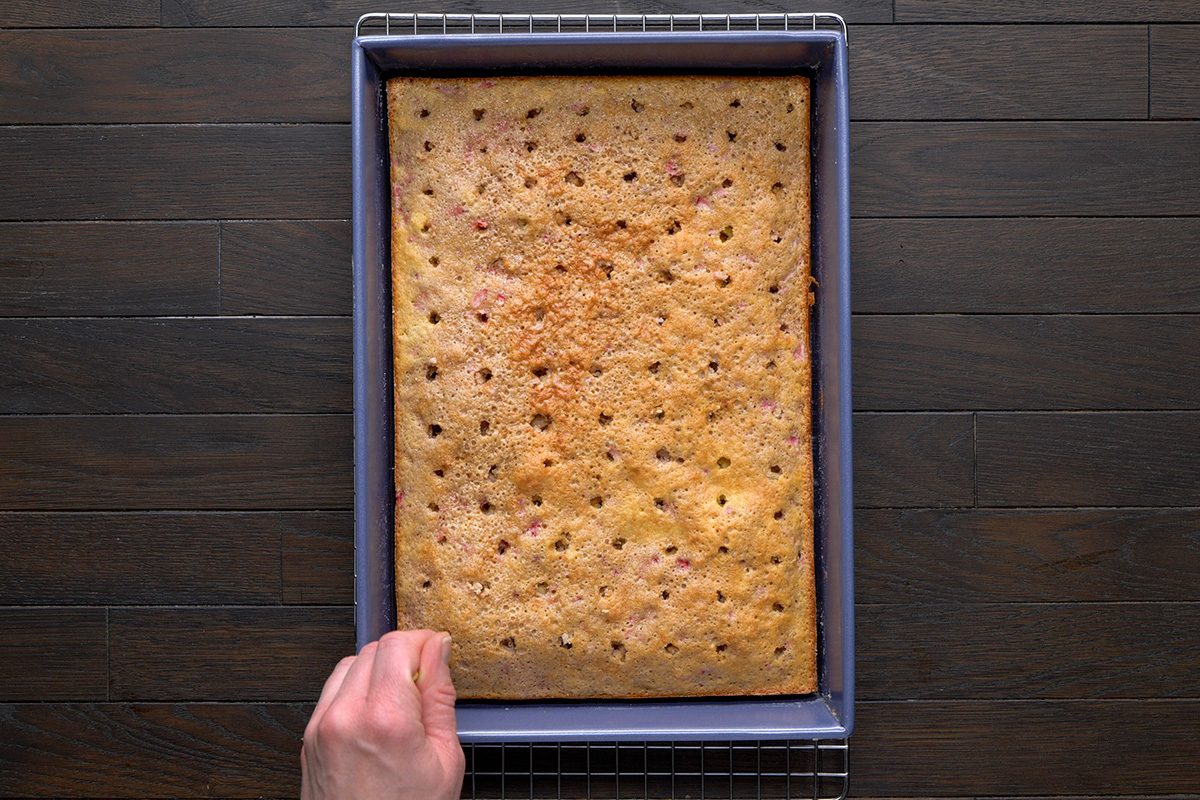 overhead shot of a golden brown baked cake; Use the bottom of a wooden spoon to poke holes in the top of the cake