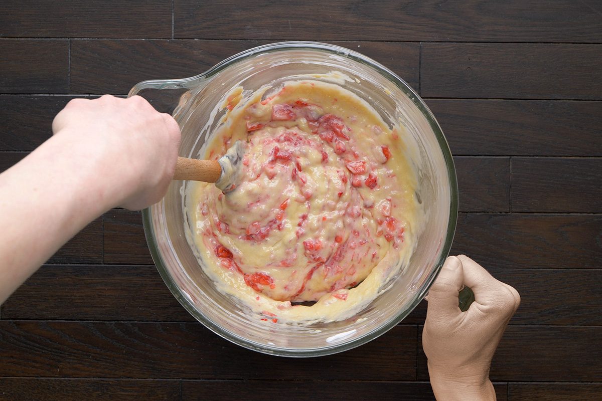 Overhead shot of a creamy batter with bits of red strawberries mixed in