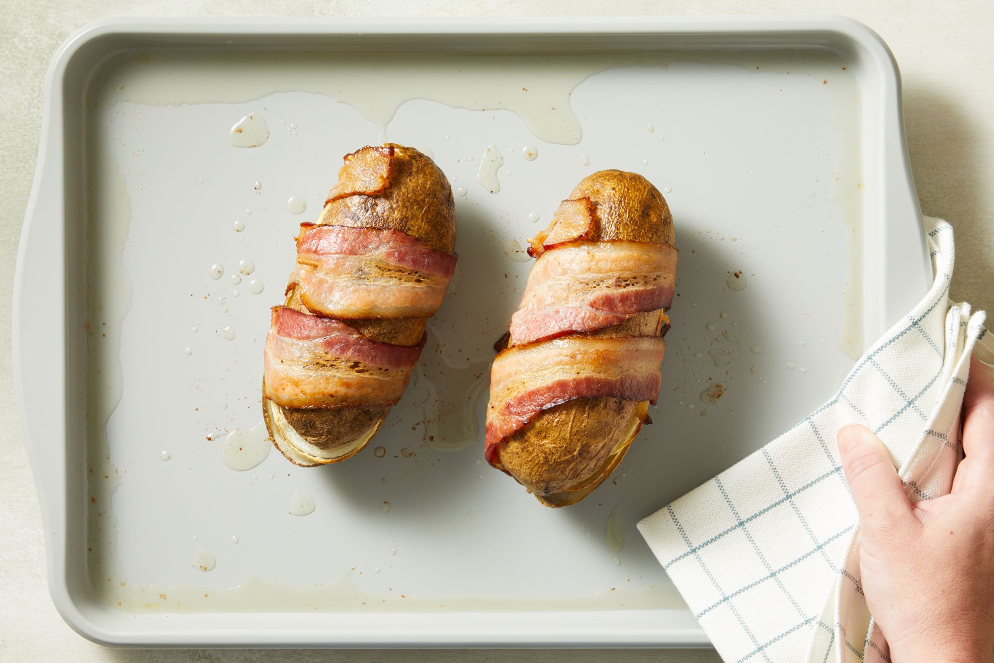Overhead shot; Place on a lightly greased baking pan; Bake uncovered at 325 degree for 1 hour and 20 minutes or until potato is tender and bacon is crispy; Discard toothpicks; napkin; all set on a marble surface