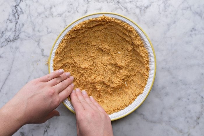 Overhead shot of Press mixture into the bottom and up the sides sides of a 9 inch deep-dish pie plate; Bake until crust is set about 15 minutes; Cool completely; all set on a marble textured surface