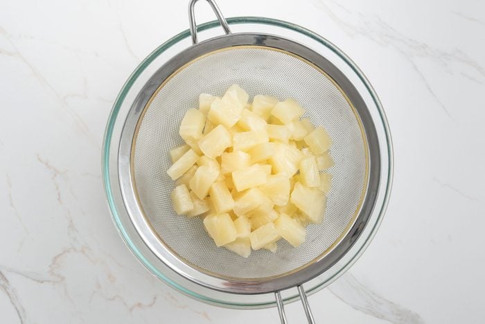 Drain pineapple in a strainer
