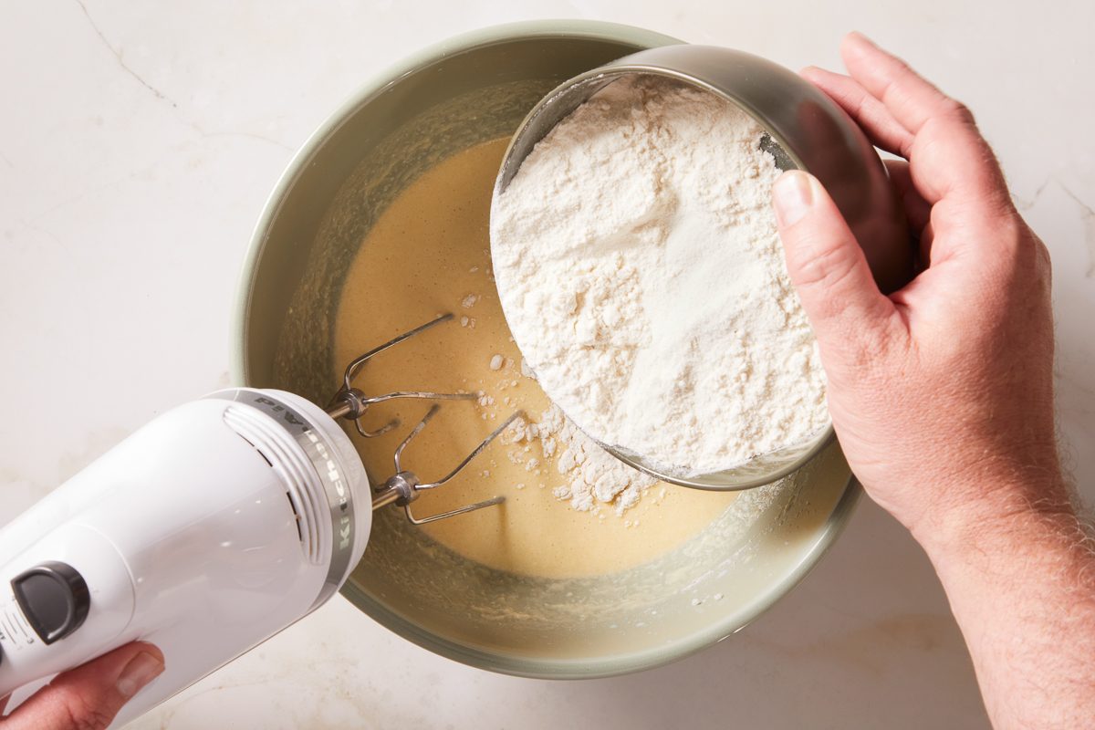 adding flour to eggs, butter and sugar mixture