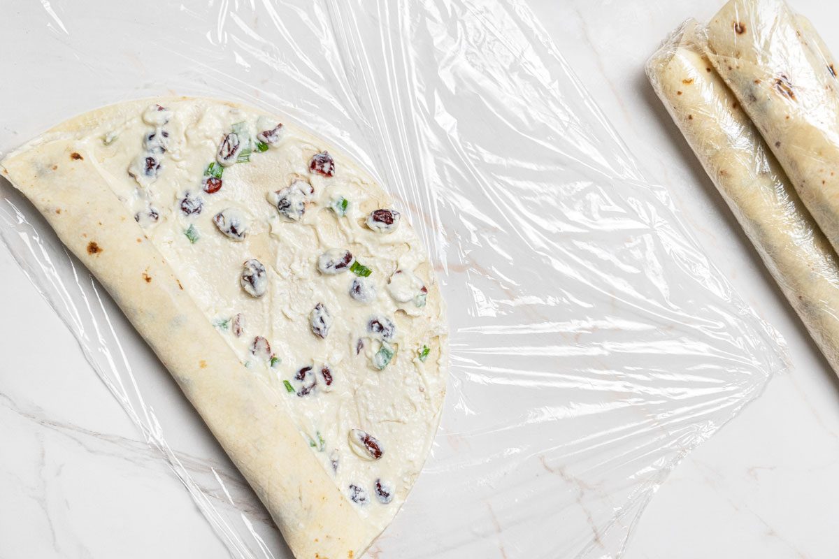 Overhead shot of roll up tightly; Wrap with plastic wrap; all set on a white marble surface;