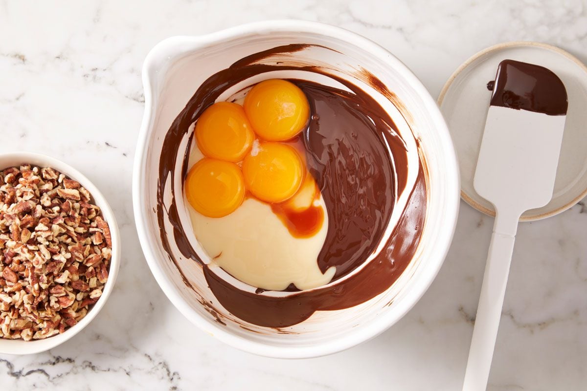 melt chocolate in a large bowl; stir until smooth.. Whisk in milk, egg yolks and vanilla;