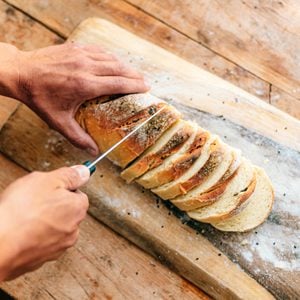 Cropped photo of men's hands slicing homemade bread