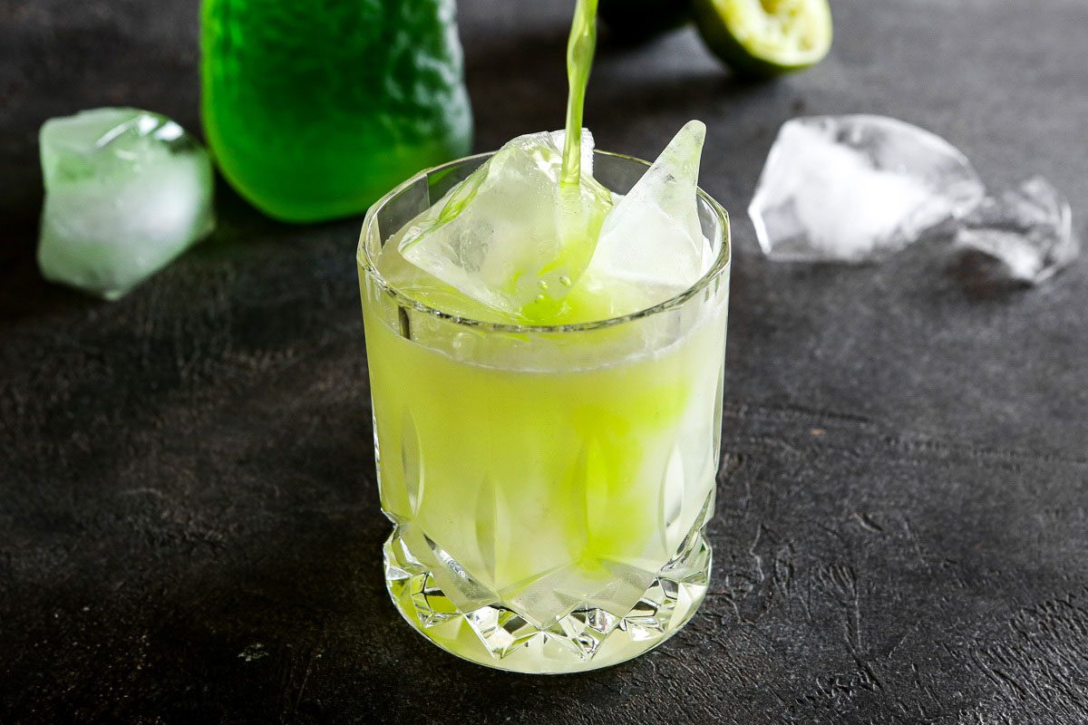 Pouring midori over the cocktail 