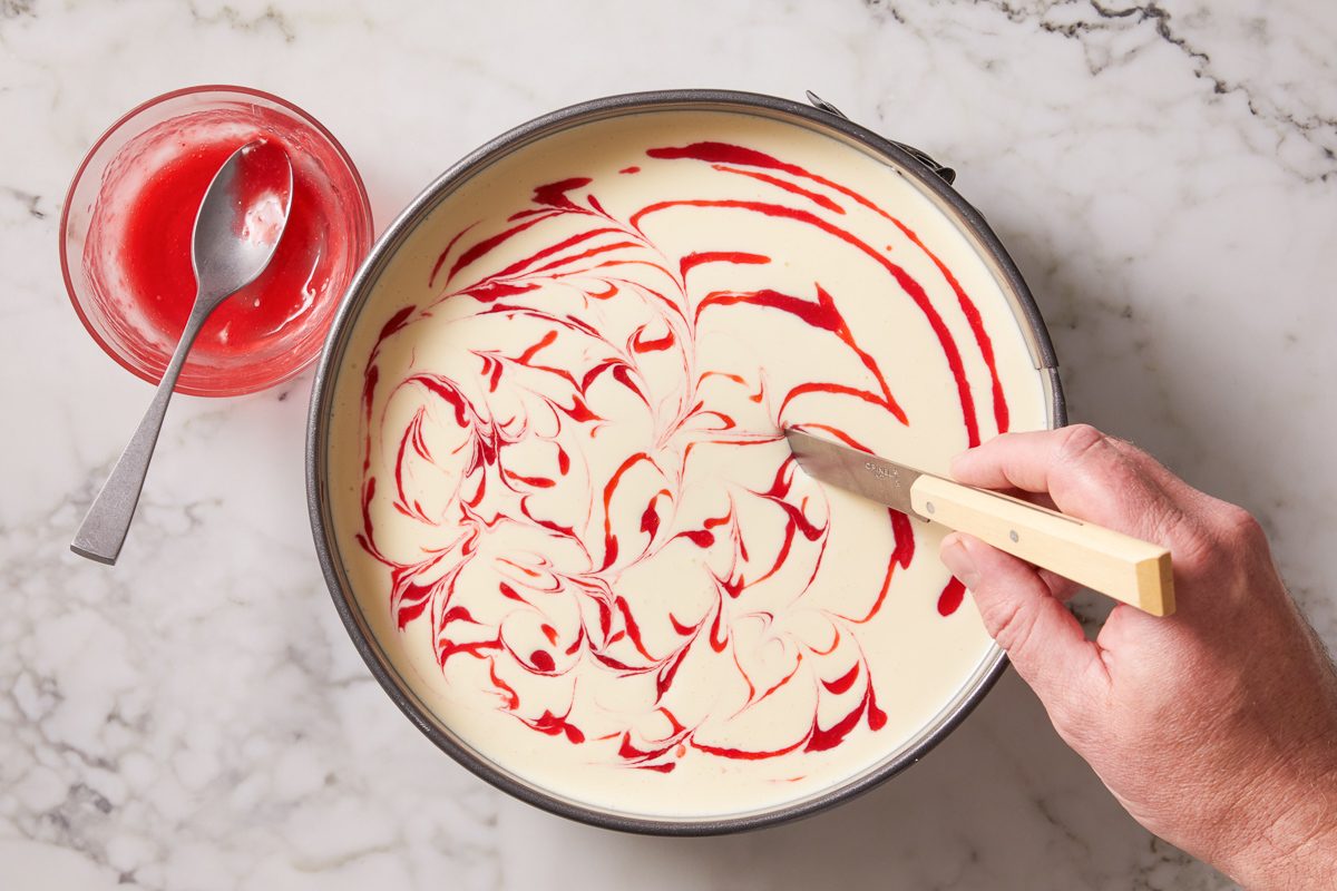 raspberry swirl being mixed with cheesecake filling