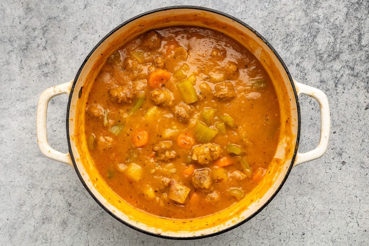 Overhead shot of the same dutch oven; Combine cornstarch and cold water until smooth; gradually stir into stew; Bring to a boil; cook and stir for 2 minutes or until thickened; on a grey marble surface;