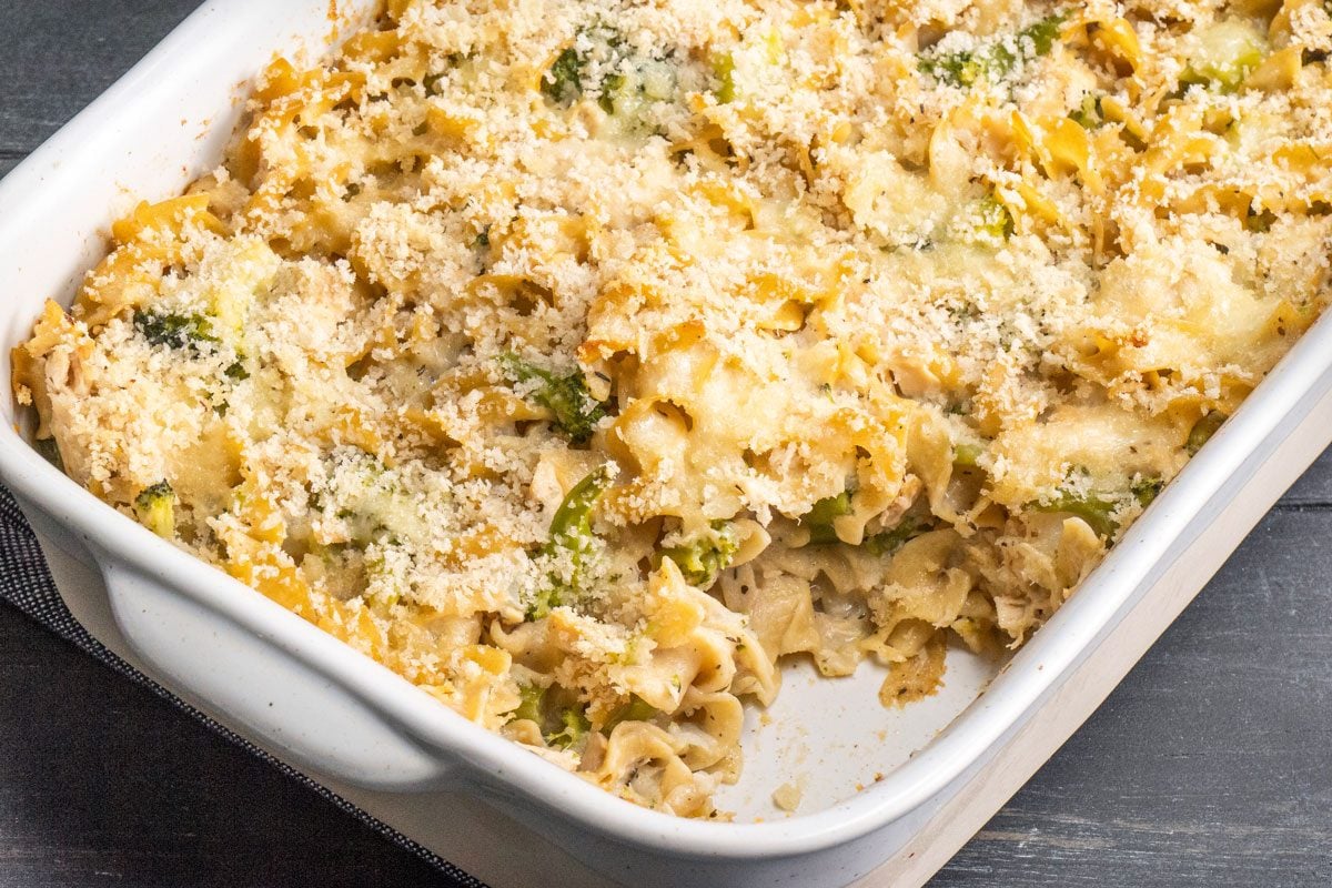 3/4th shot of a white casserole dish holds baked noodles; broccoli; and is topped with golden-brown melted cheese and crispy breadcrumbs; creating a comforting meal; Tuna Broccoli Casserole;