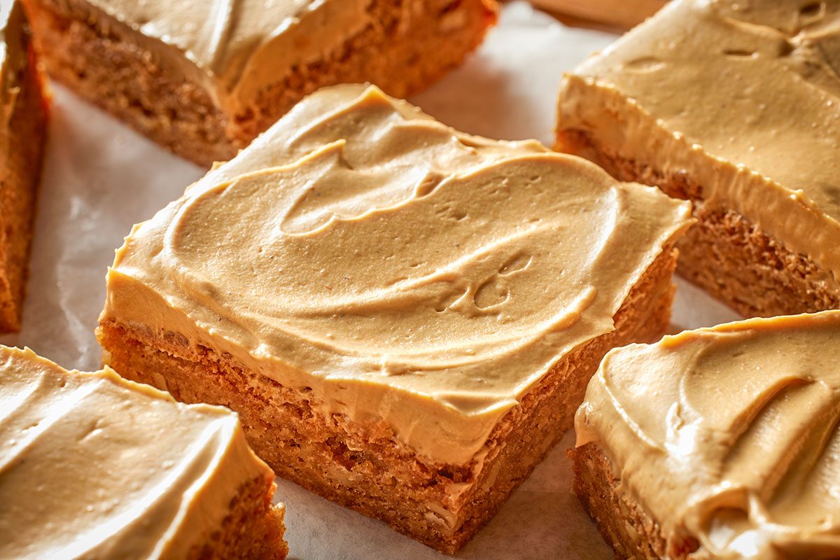 Close-up shot of brown butter blondies topped with swirls of speculoos buttercream; arranged on parchment paper;