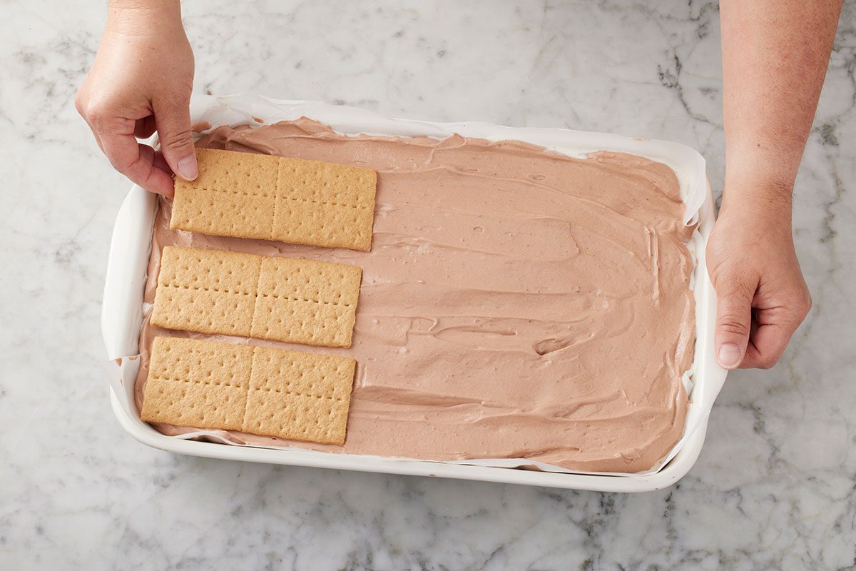 Another layer of graham cracker being lined up on the top