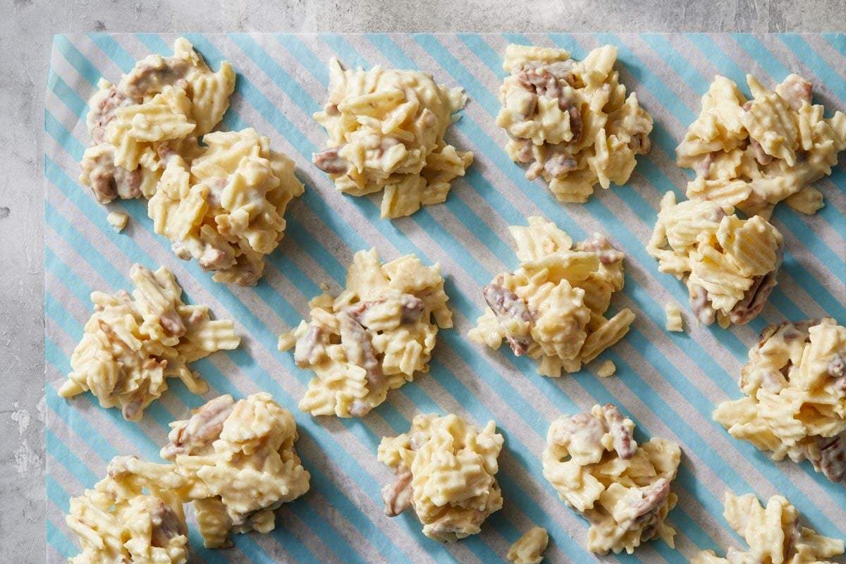 Overhead shot of Potato Chip Clusters arranged on a blue-and-white striped sheet; set on a grey surface.