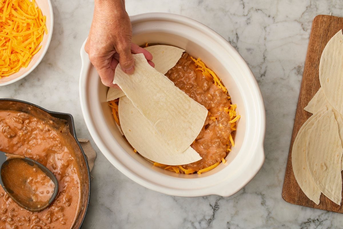 In a 3-qt. slow cooker, layer a third of the beef mixture, tortillas and cheese.