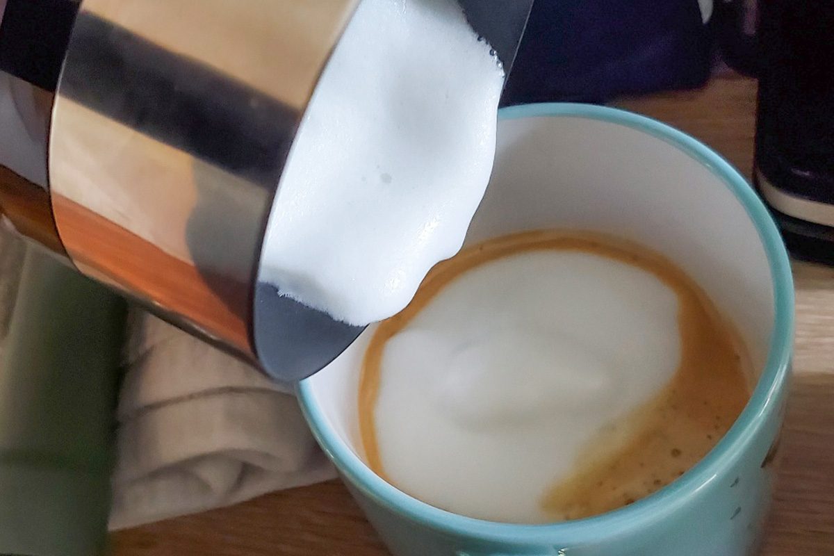 pouring hot foam into coffee cup