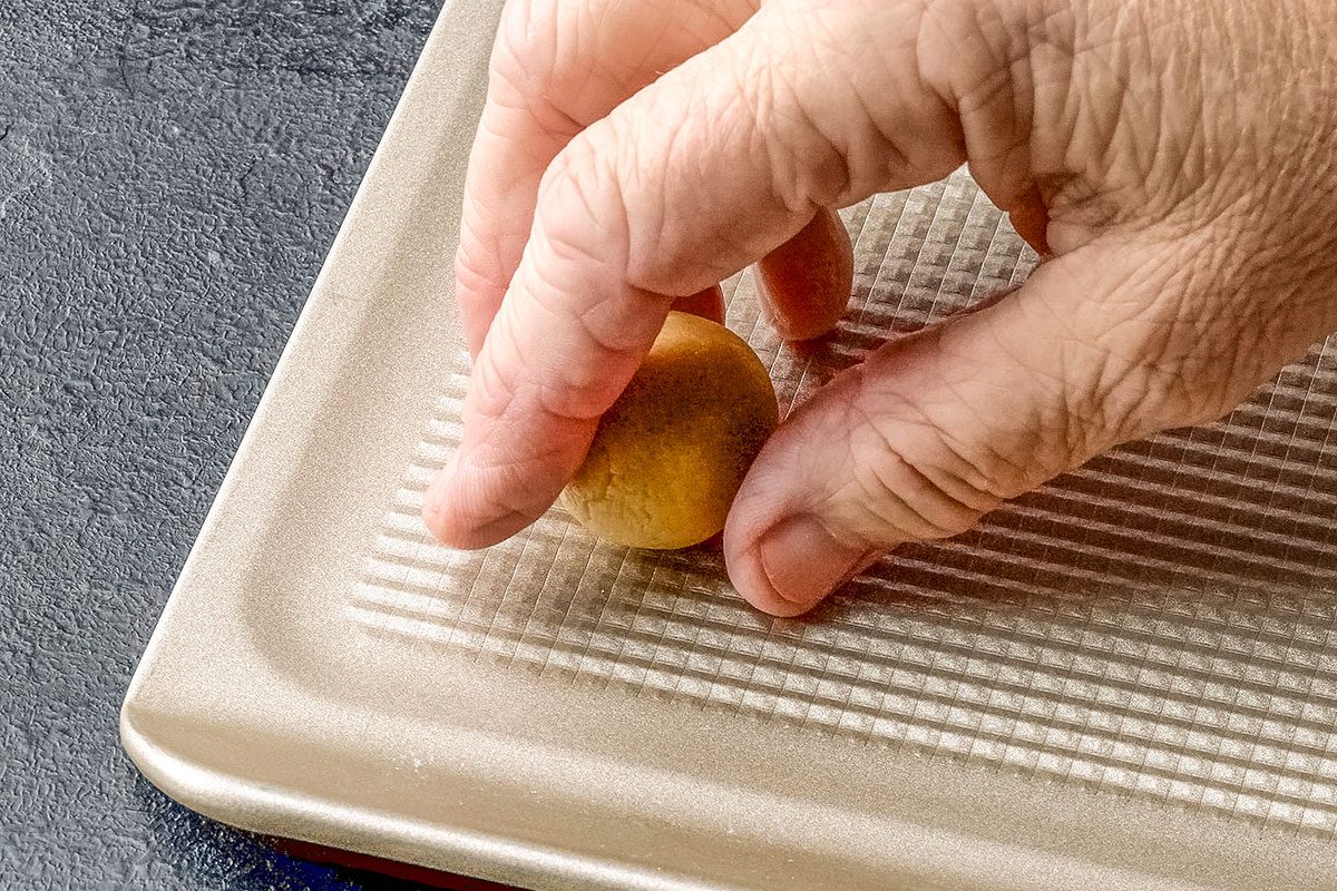 Close shot of shape into 1-inch balls; Place 2 inch apart on ungreased baking sheets; dark surface