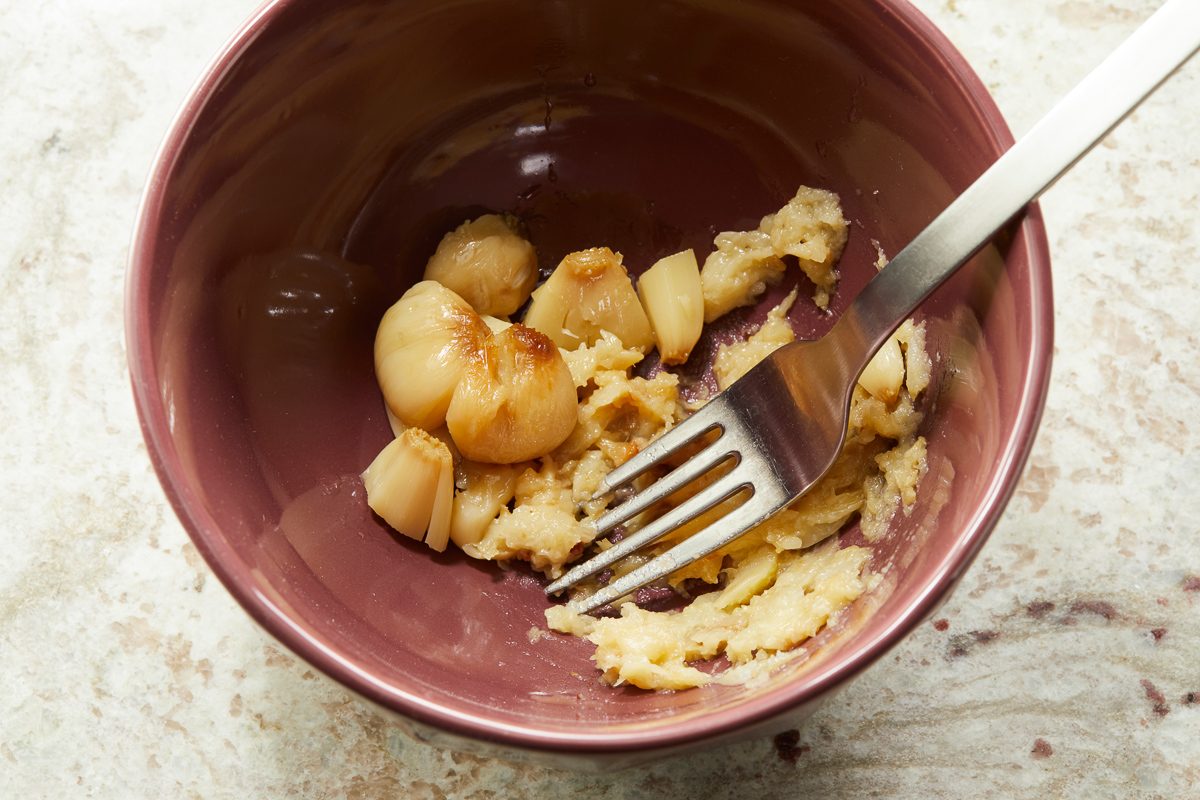 mashing squeezed garlic cloves with fork