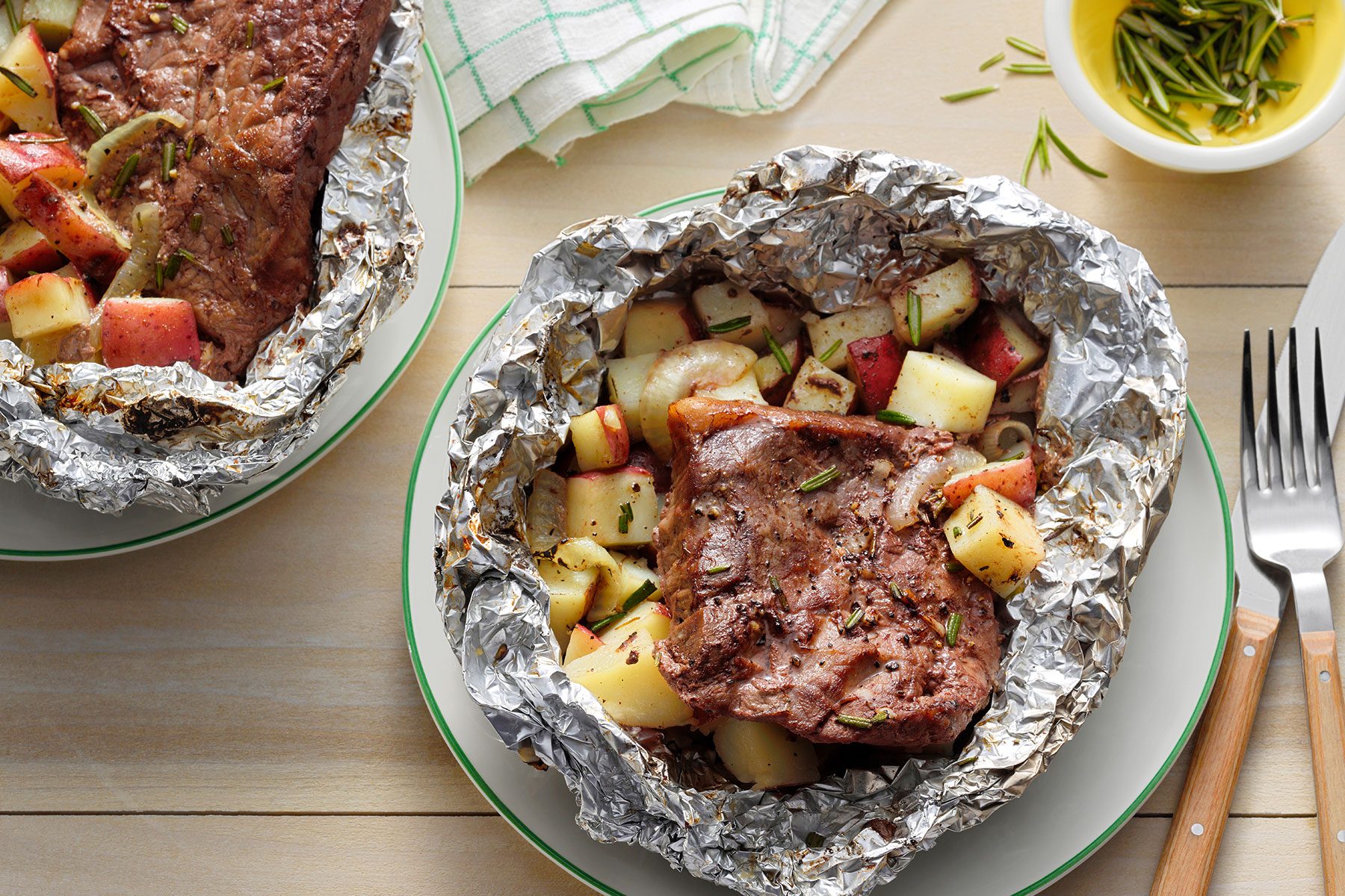Steak And Potato Foil Packs opened and placed in a tray with garnishing bowl on side.