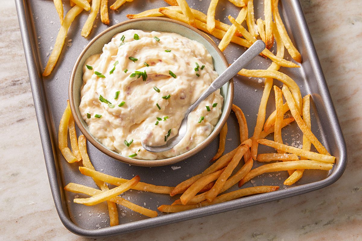 Overhead shot of Bacon Aioli in a bowl placed on a baking tray, surrounded by golden fries for a casual, shareable presentation.