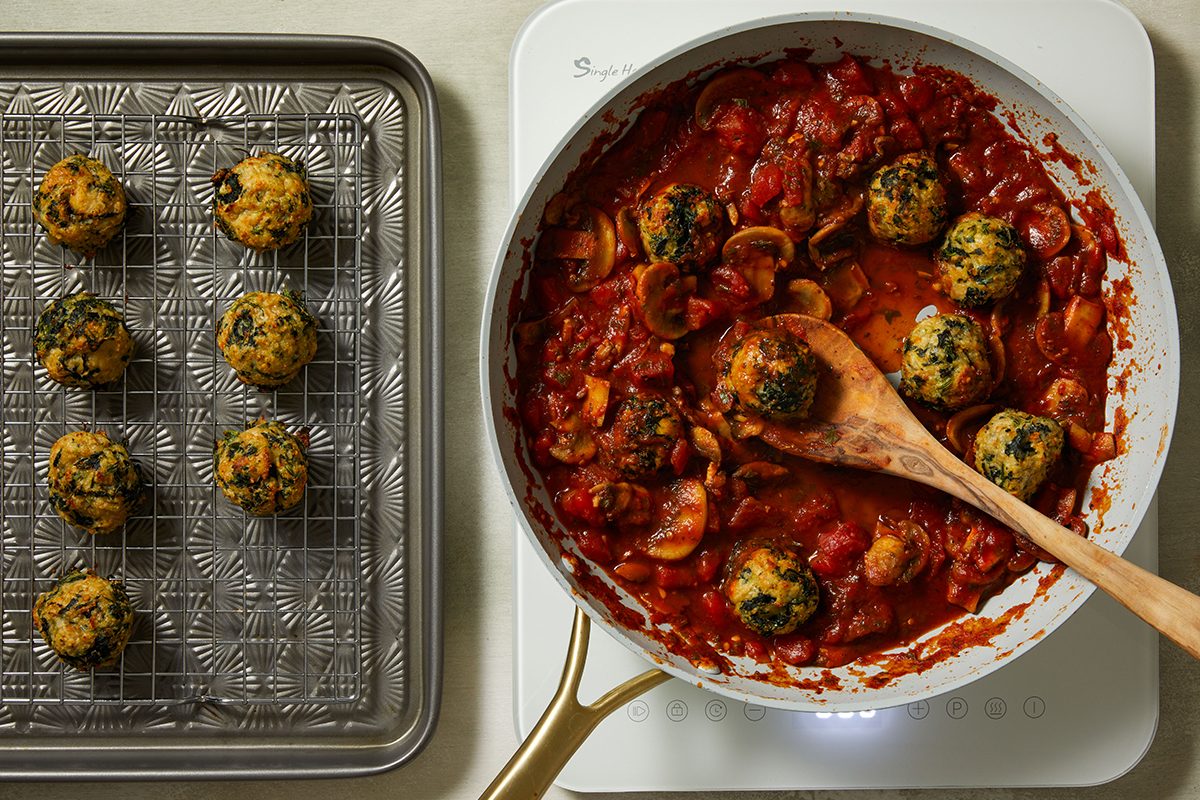 Adding meatballs to the sauce for Chicken Florentine Meatballs