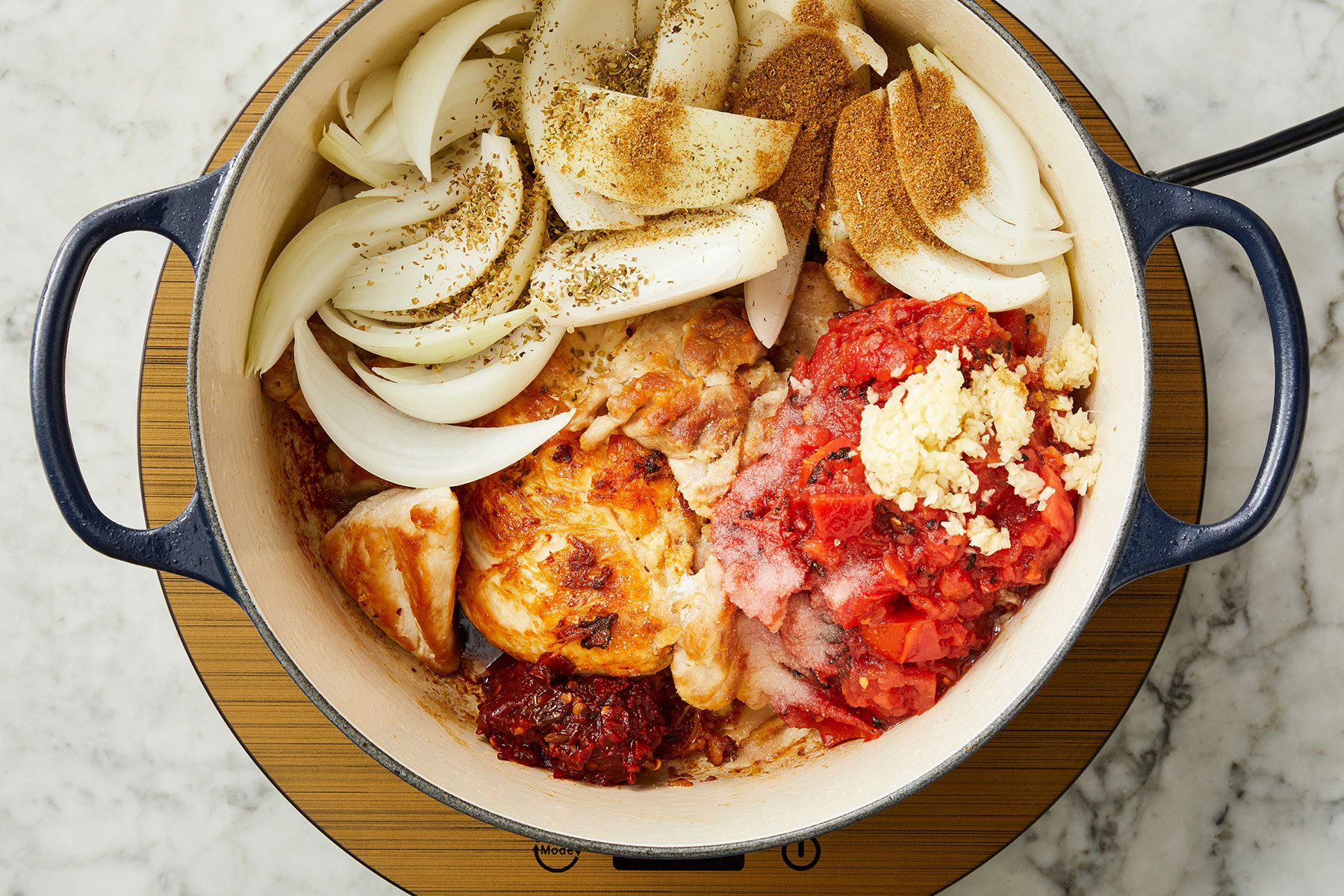 Added onion, tomatoes, broth, chipotle peppers, garlic, cumin, oregano and salt to chicken in a pan.