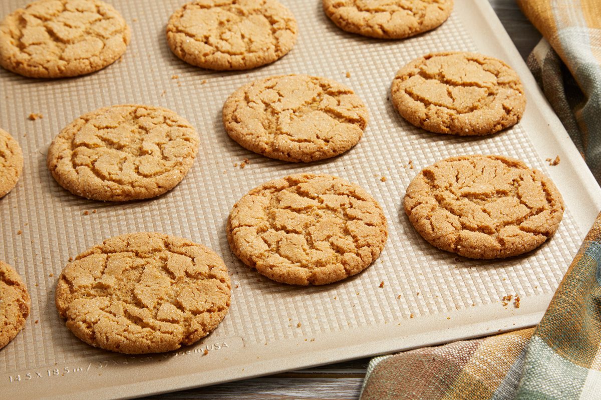 3/4 shot of Cinnamon Crackle Cookies resting on a parchment-lined baking sheet, with some cookies slightly overlapping each other.