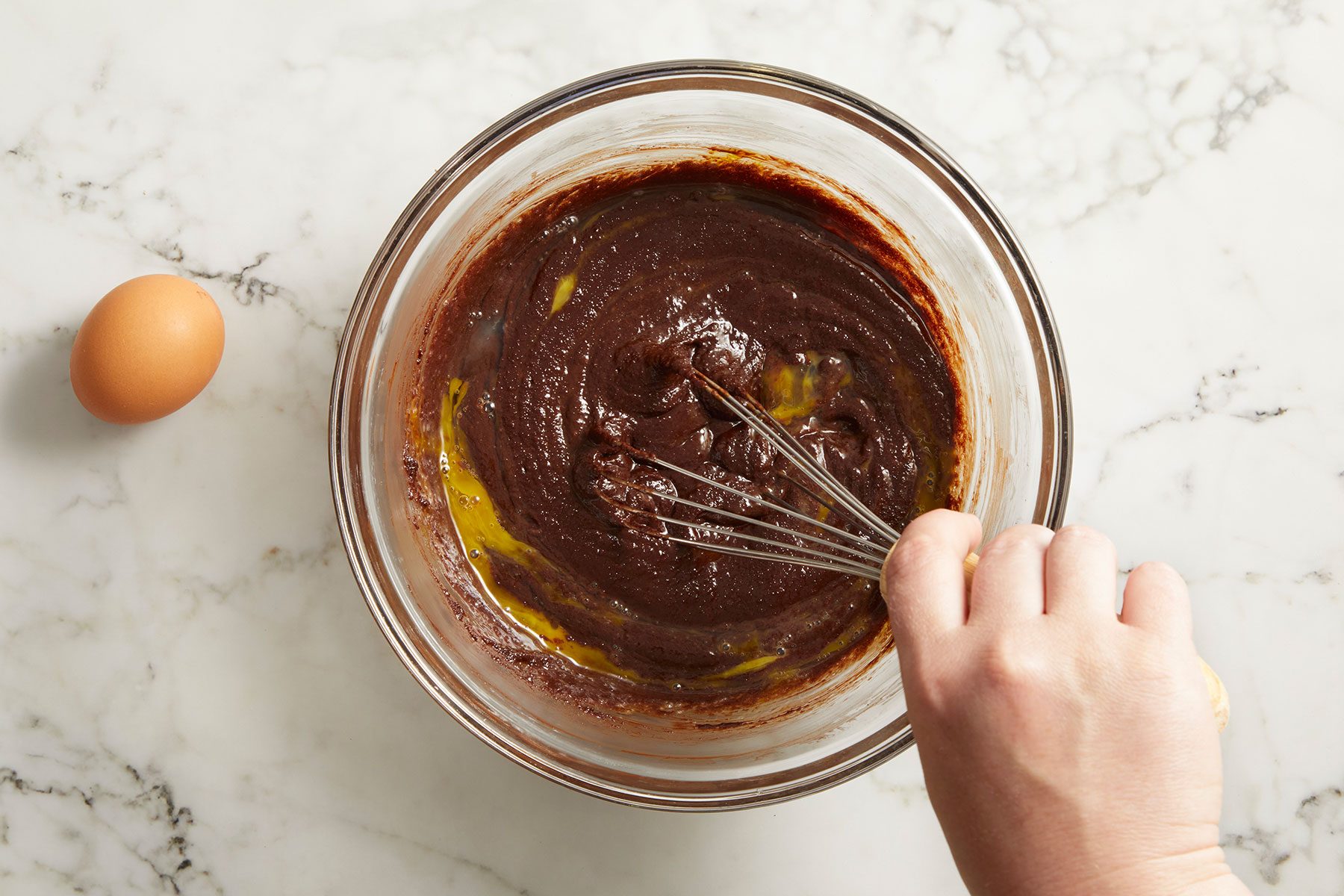 Added egg to the brownie mixture and stirring using a whisk.