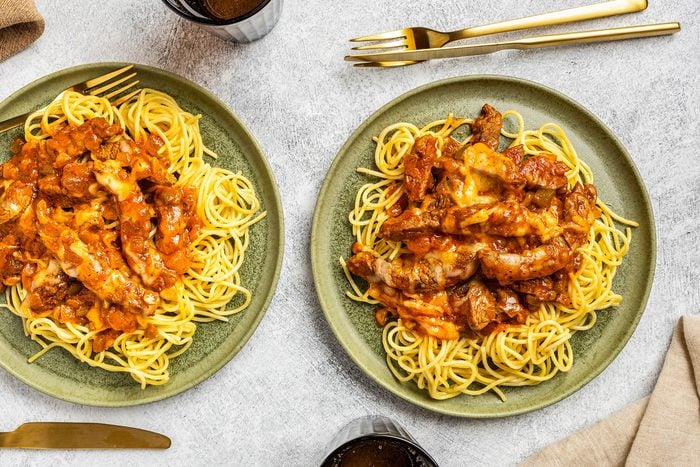 Steak And Spaghetti in two plates with forks kept on side.