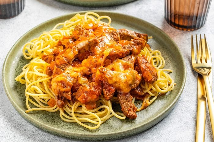 Steak And Spaghetti on a plate with a fork kept on side.