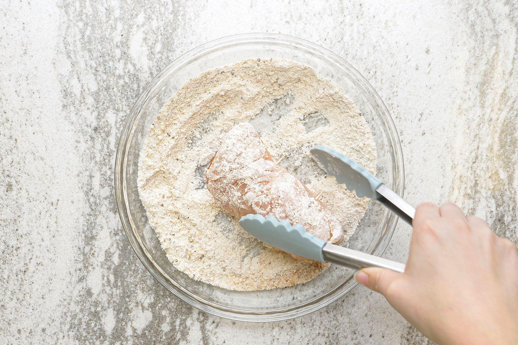 Rolling chicken bundles in the flour mixture, coating all sides.