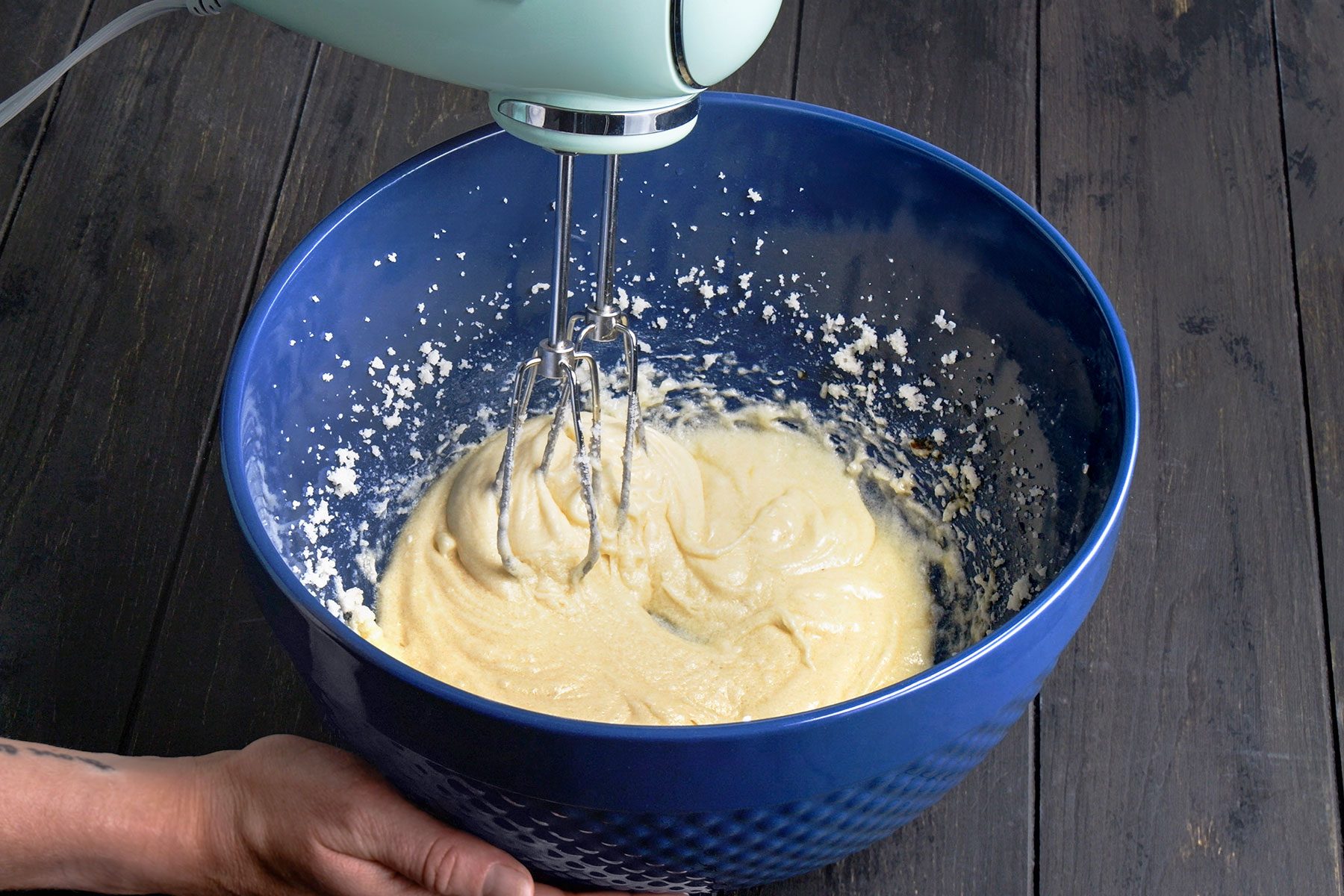Beating eggs into butter and sugar's creamy mixture.
