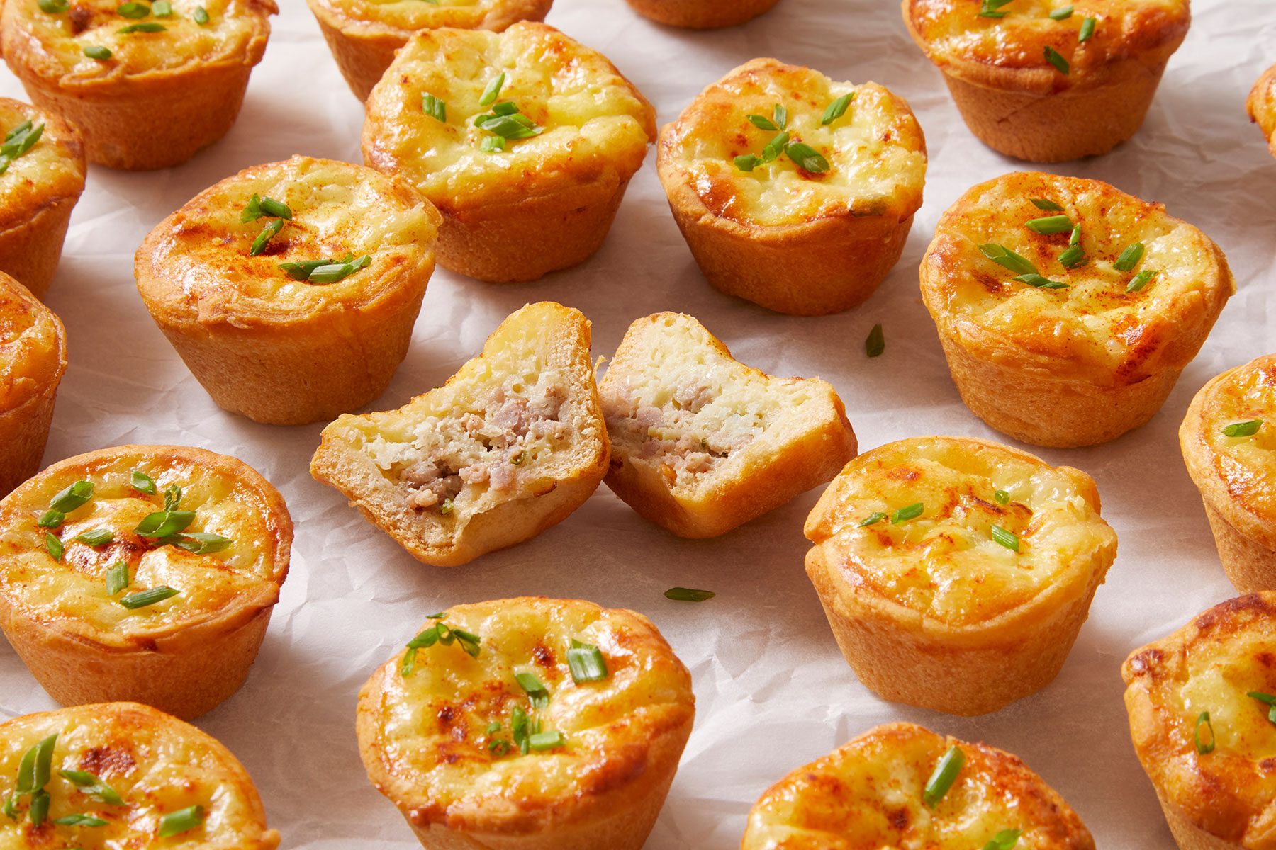 Mini Sausage Quiches on parchment paper.